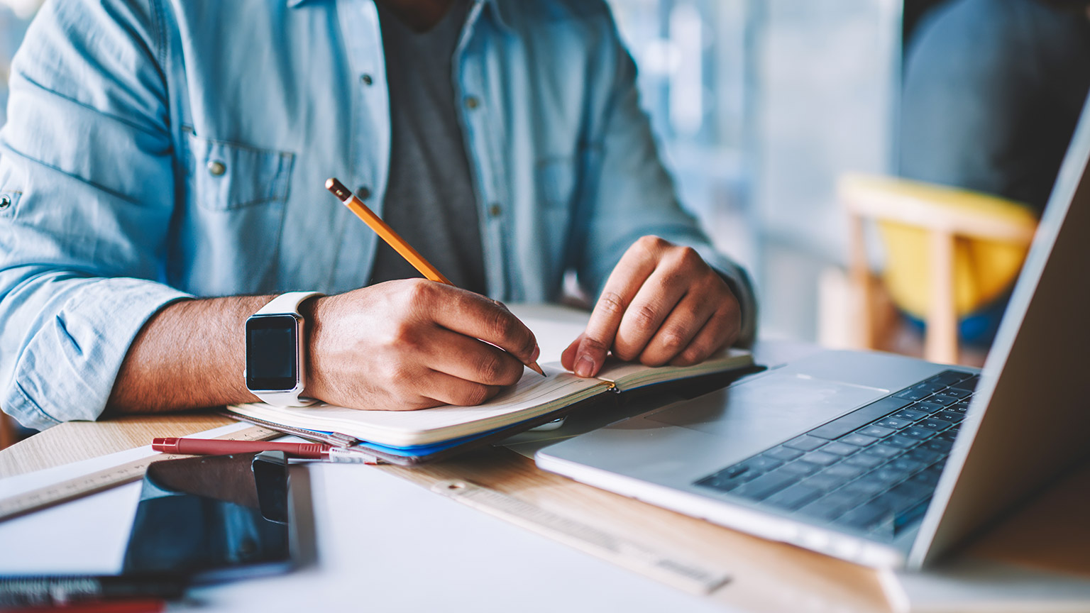 Male designer at desk writing on a notepad