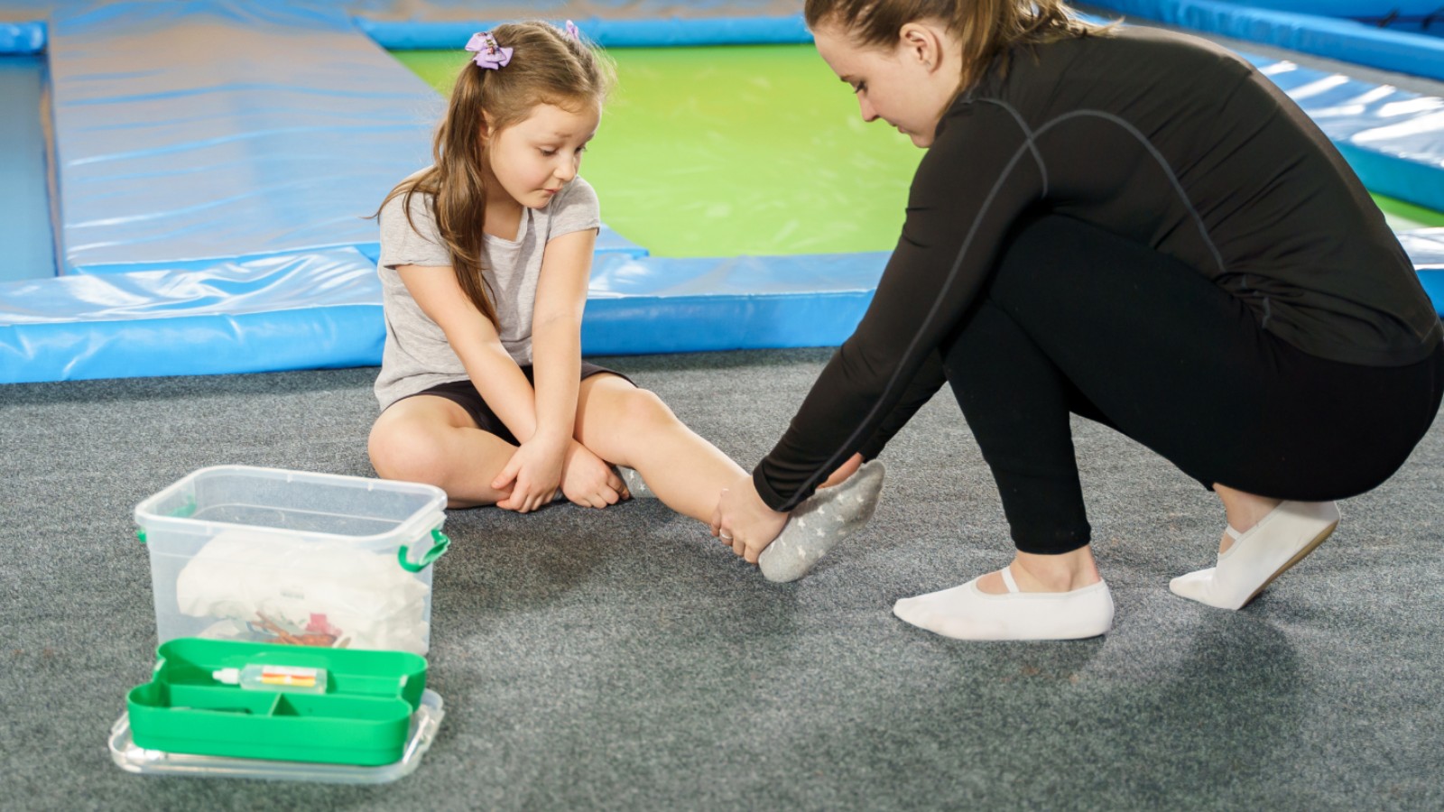 Young girl receiving first aid for an ankle injury