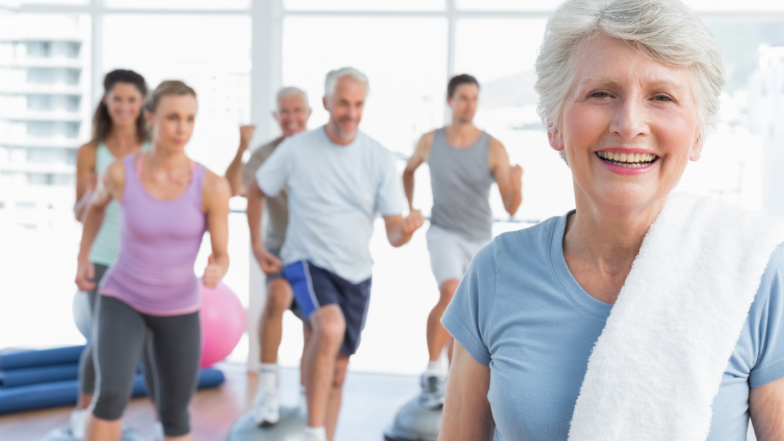 Elderly woman in foreground with a group exercising behind her