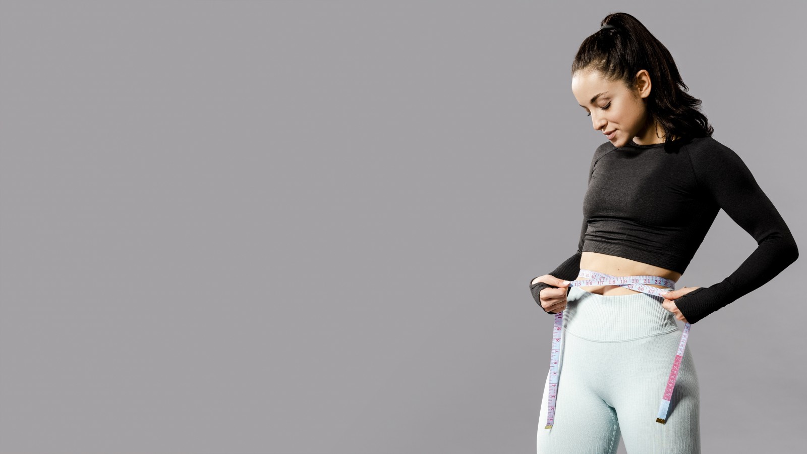 Woman in fitness attire measuring waist