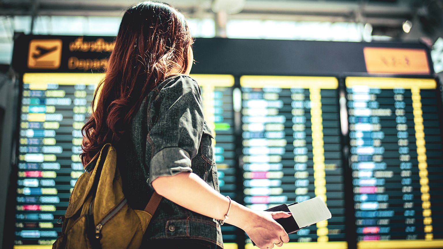 Woman at airport looking at departure board