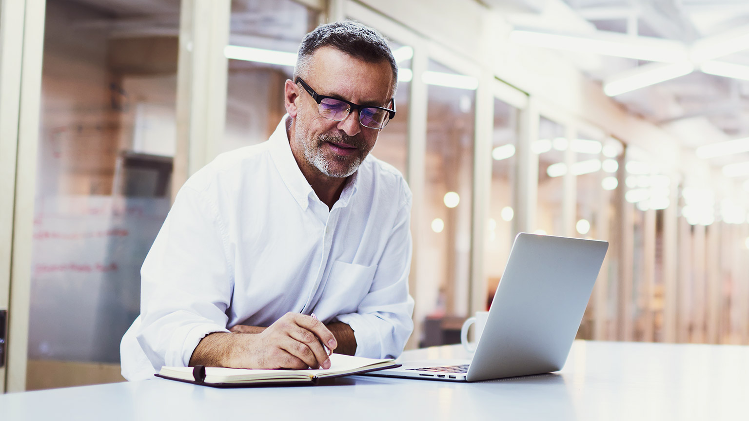 Middle-aged business man with laptop and pen and paper