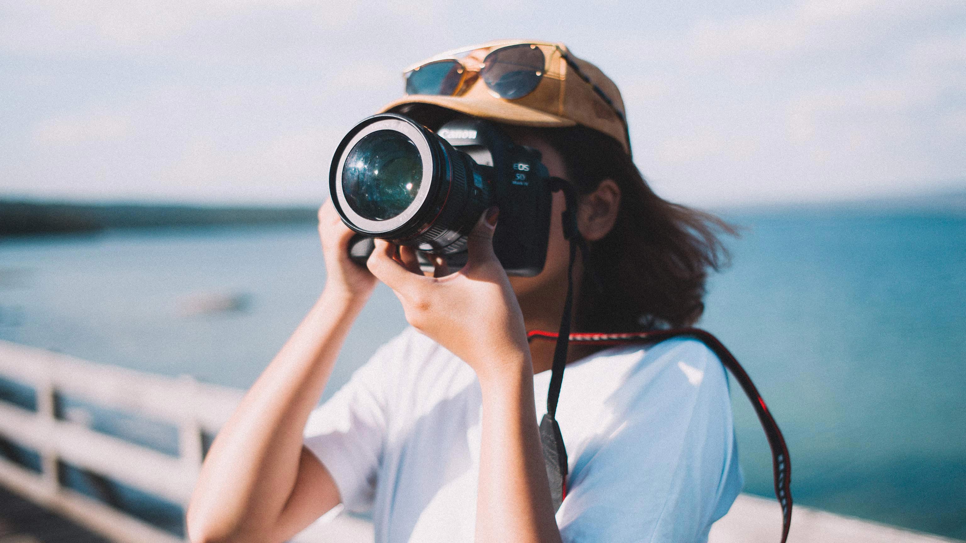 A woman taking a photo from a pier, on a sunny day