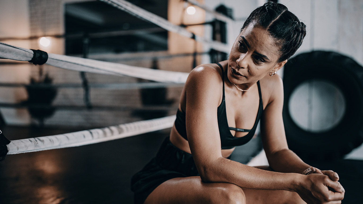 Women sitting on side of boxing ring looking worn out