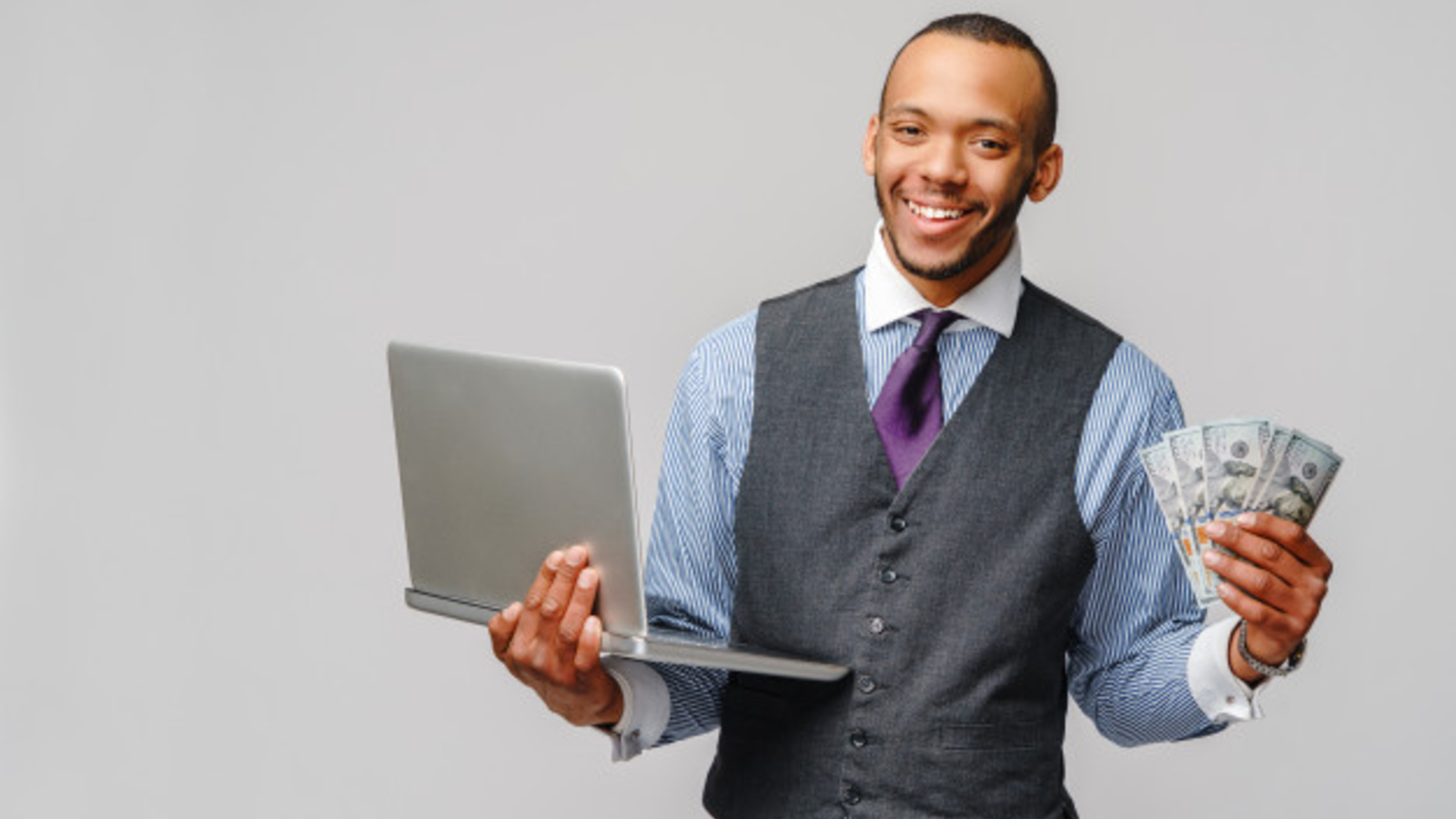 young business man holding cash and laptop