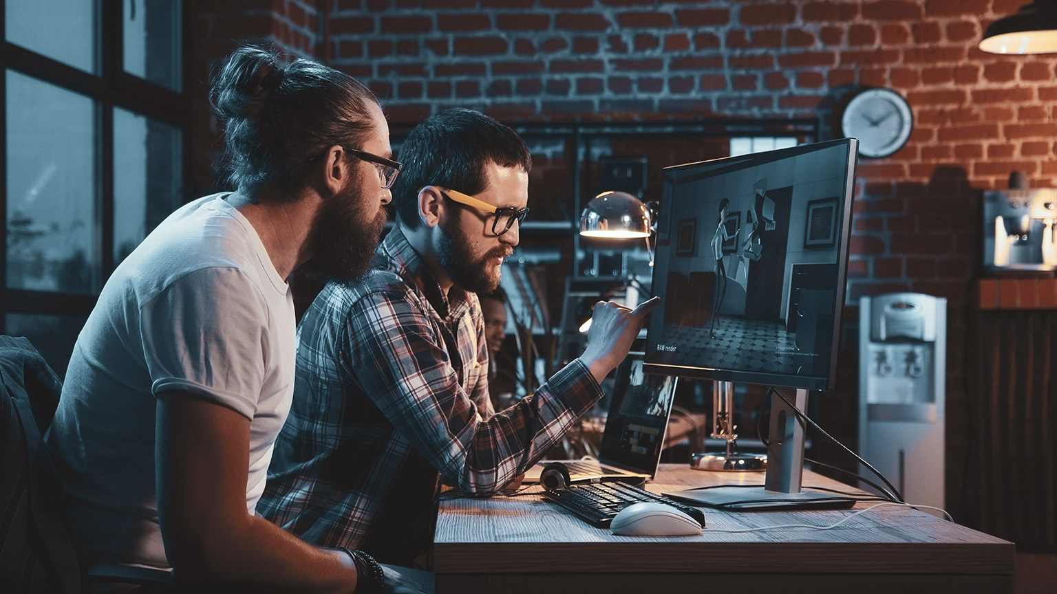 2 animators working at a desk looking at a computer screen