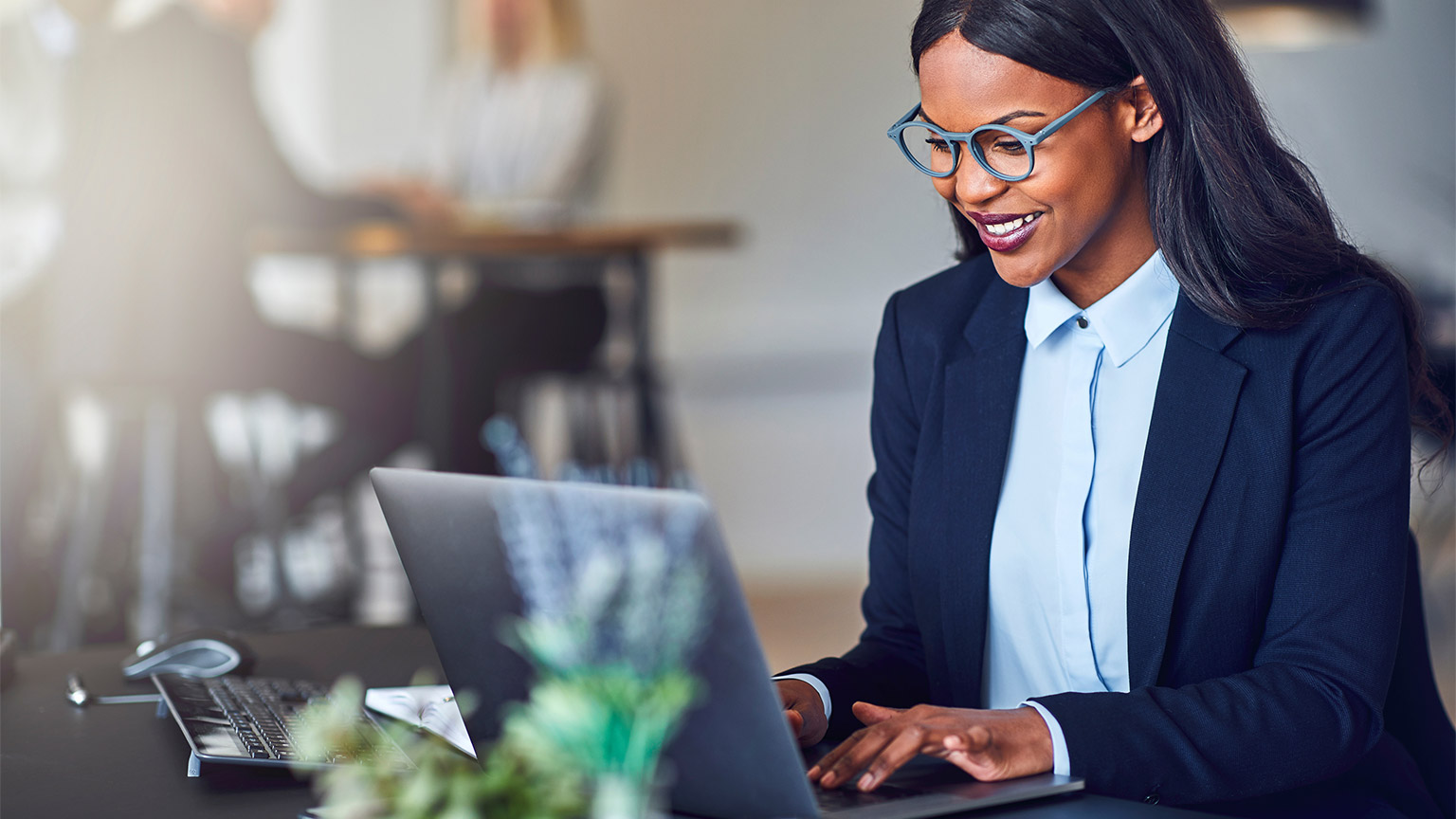 A professionally dressed woman working on her laptop in an office