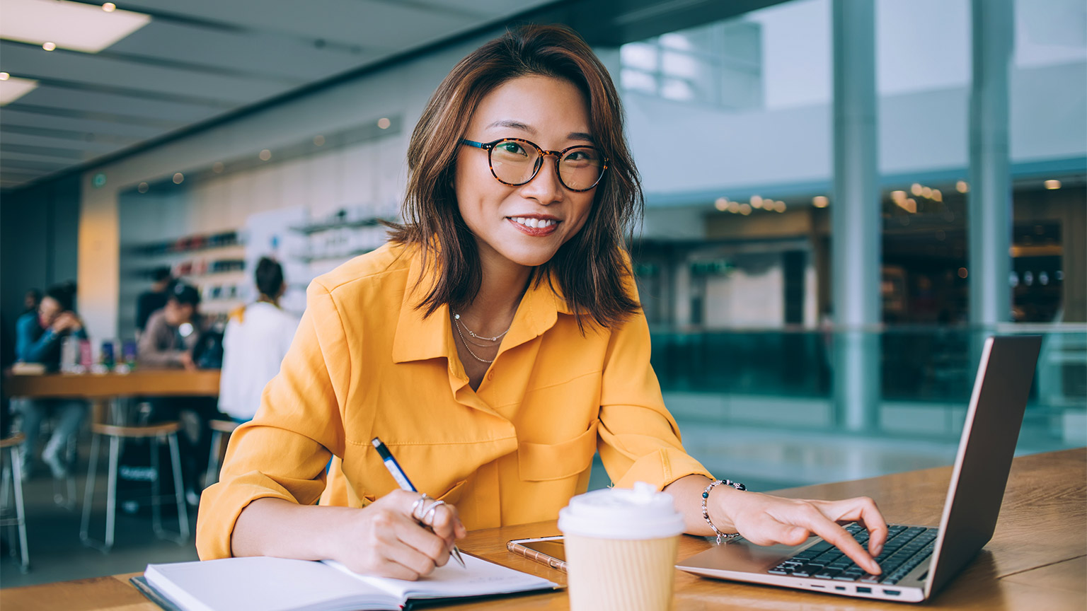 A woman recording data, while working remotely from her laptop