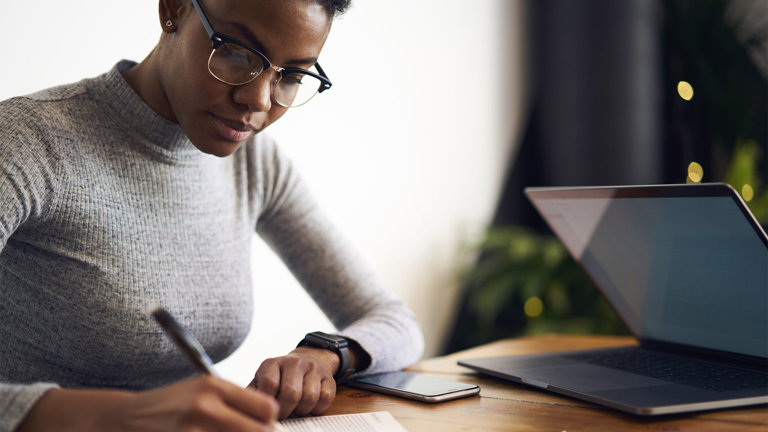 A person writing down notes in front of their laptop