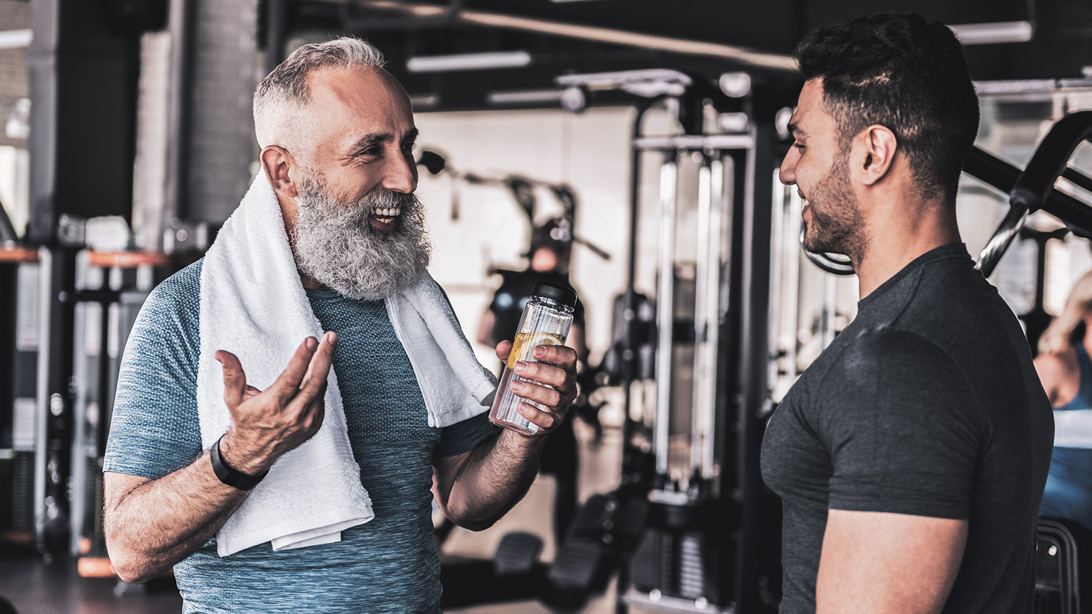 Male trainer talking to smiling mature male client