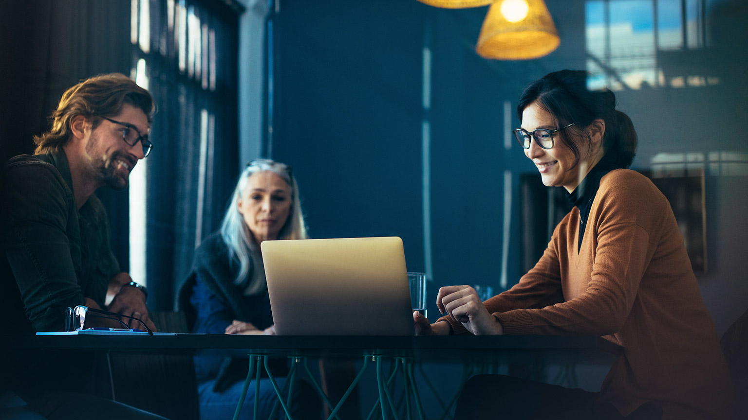 Business colleagues sitting around a table looking at a laptop