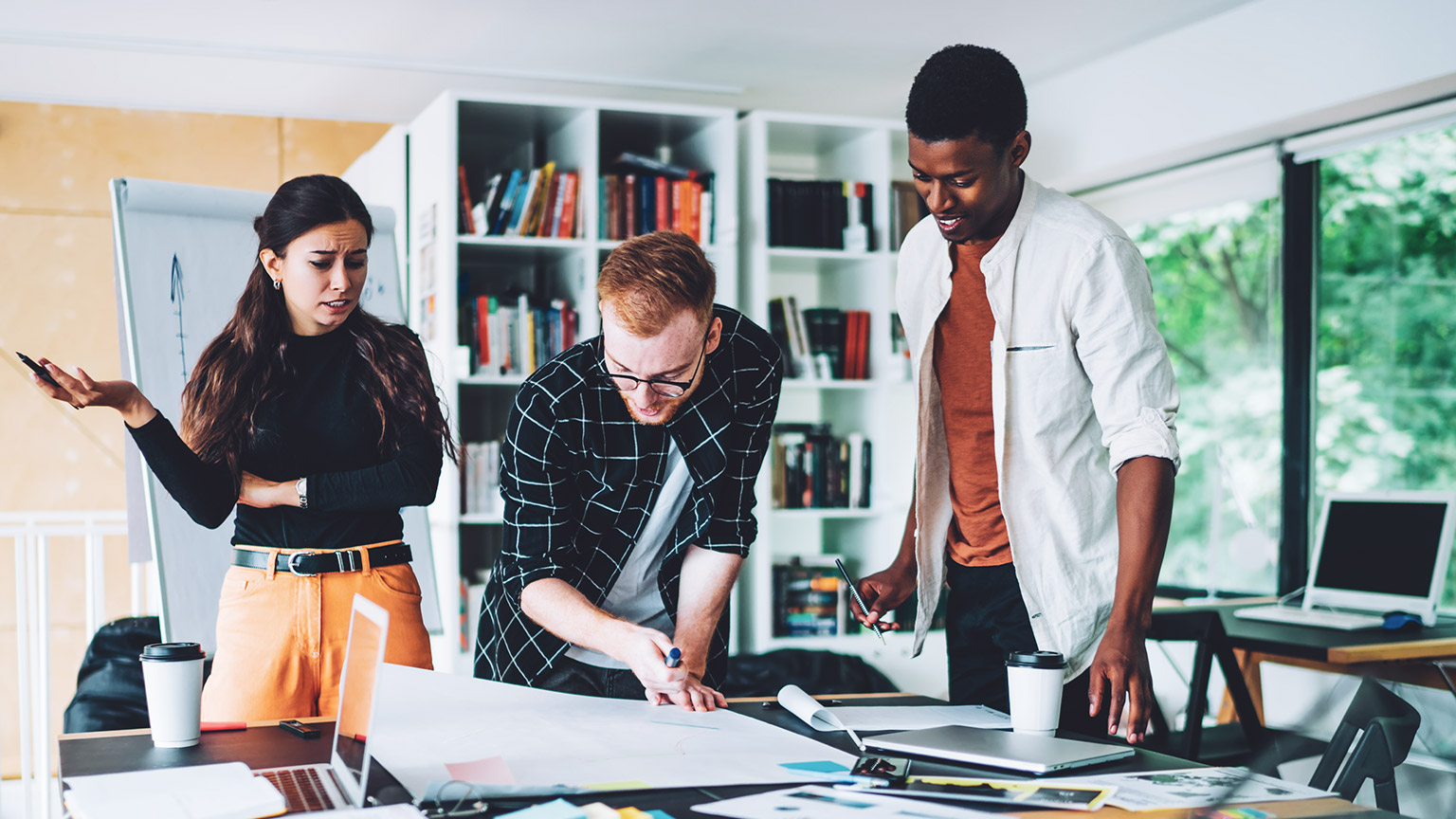 3 young professionals discussing a plan on a table in a casual office space