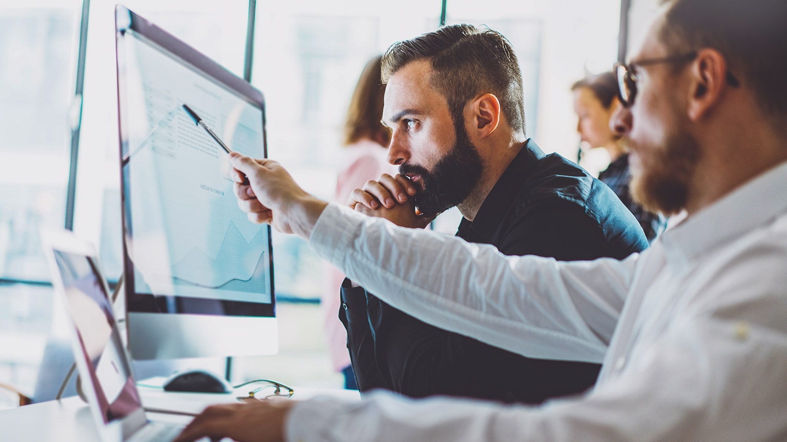 Coworkers looking at computer screen with accounting information on the screen