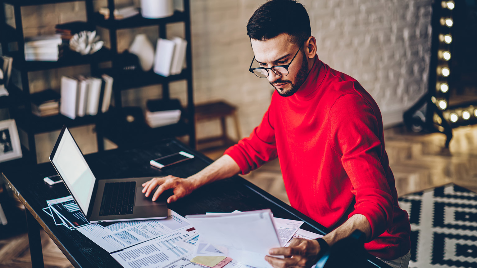 A person absorbing a document at their desk in their home