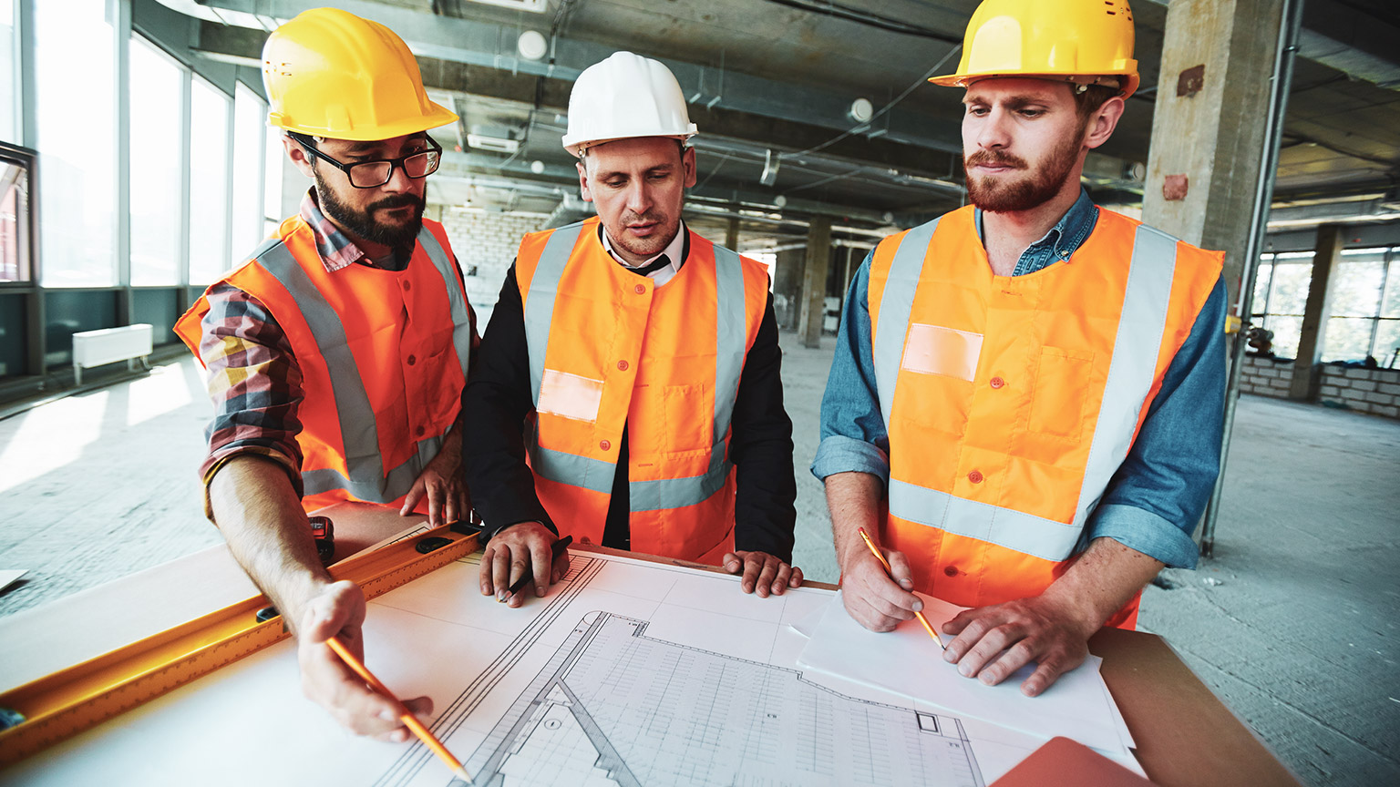 3 coworkers discussing building plan on a work site