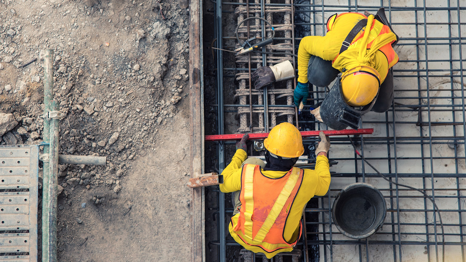 Construction workers securing reinforced steel mesh before a concrete pour