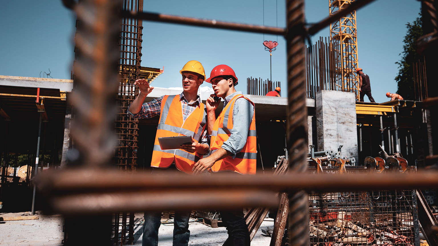 2 supervisors on a buiding site talking about the job and holding a clipboard