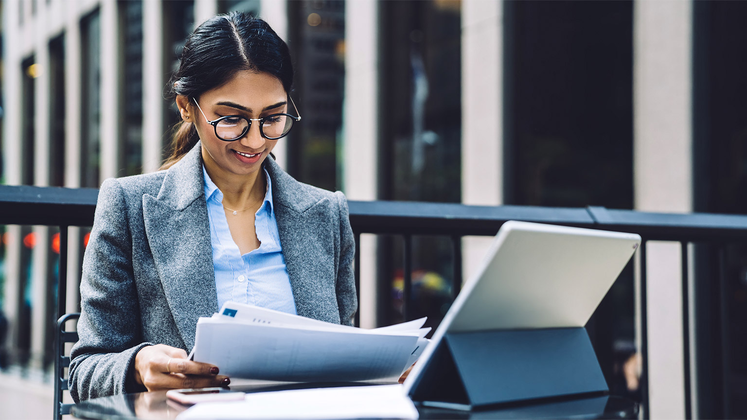 A professional seated outside reviewing a number of financial reports