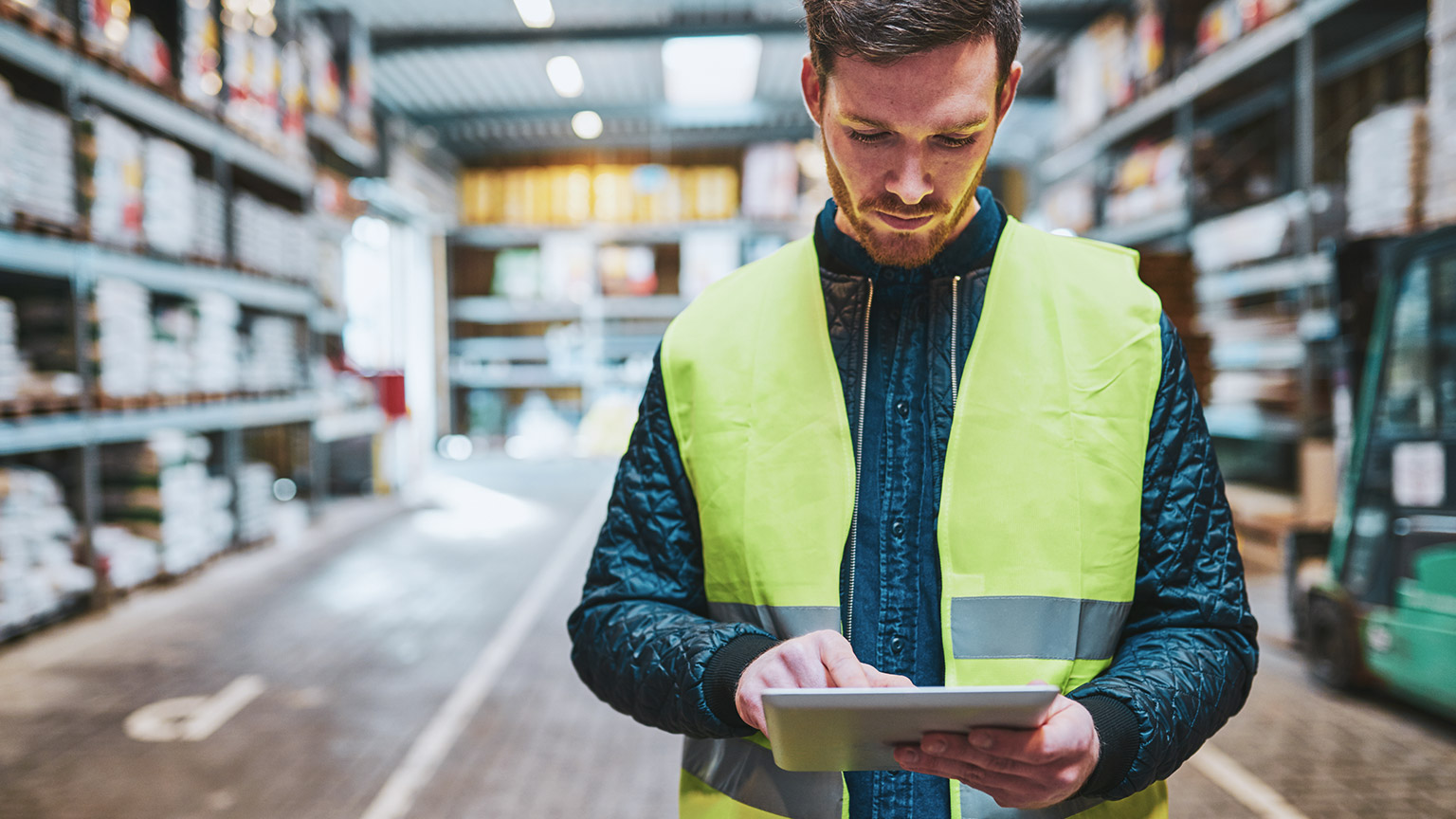 A construction worker in the materials section of a supply store, consulting list of resources required on a tablet device