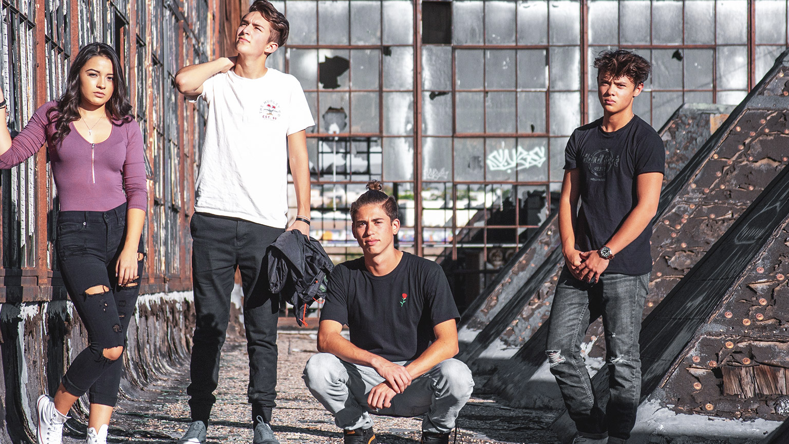 A group of teenagers standing in a grungy industrial landscape