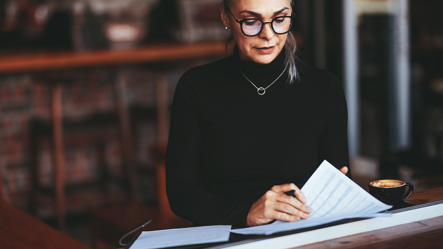 A female accountant checking over documents while working in a cafe