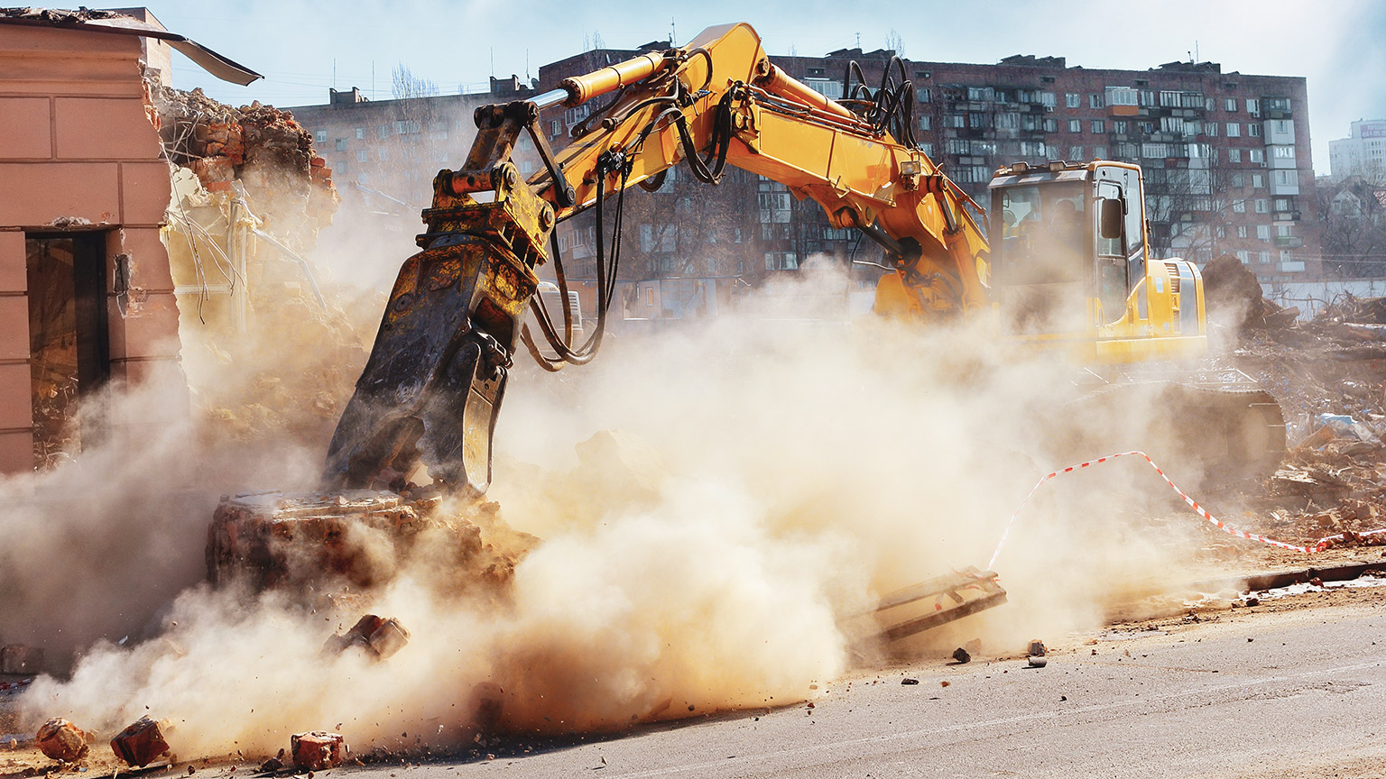 An excavator on a worksite demolishing part of a pre-existing structure