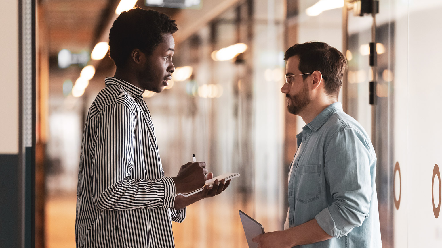 Two colleagues standing in a hallway discussing a Work, Health and Safety issue