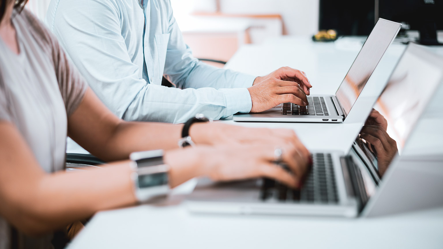 A close view of 2 business professionals typing up documents on laptop computers