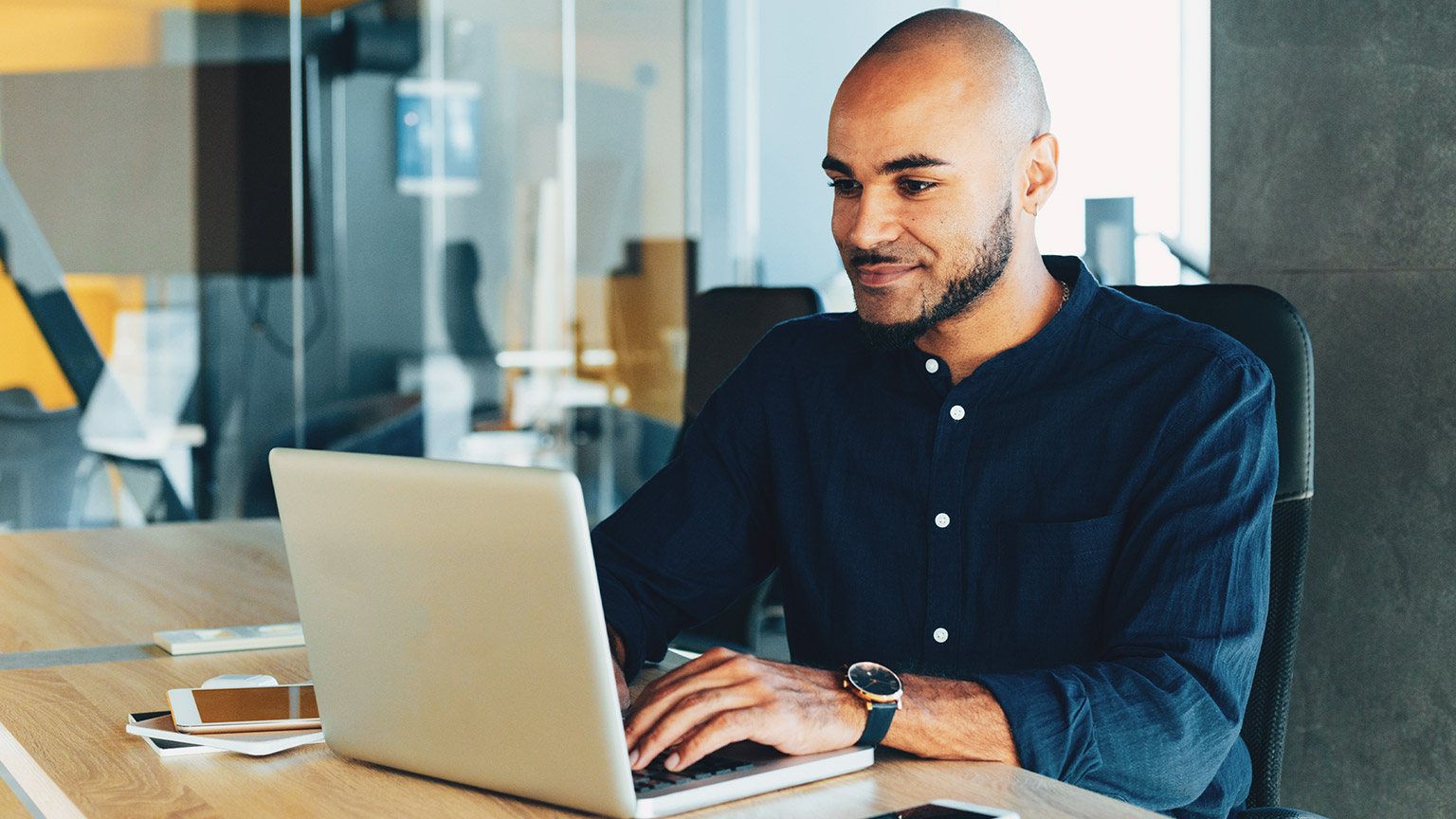 A business person sitting at a desk entering financial data into a laptop