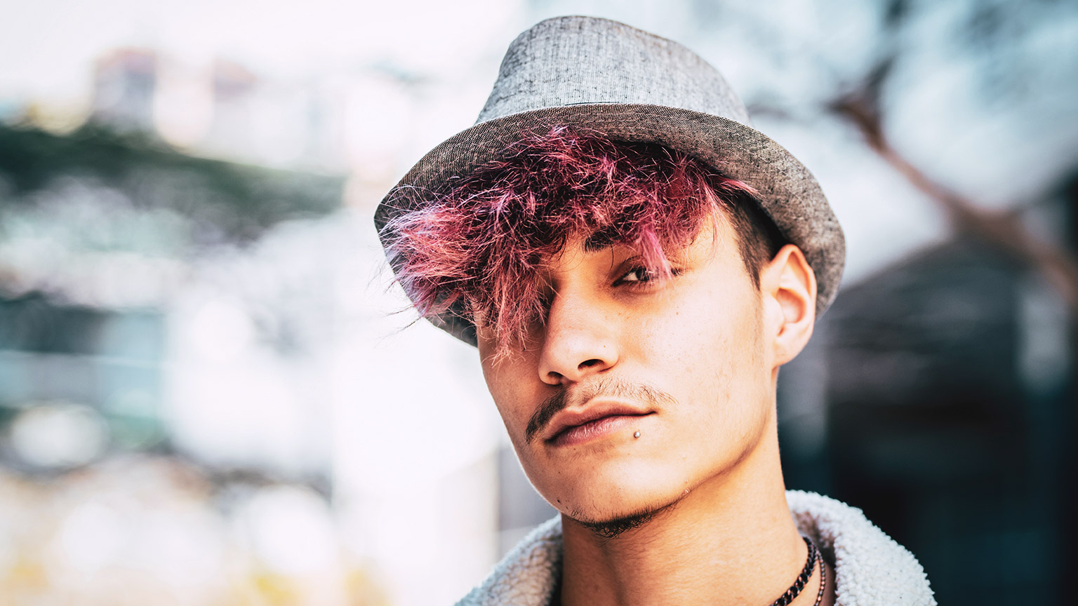 A close view of a teen with pink-tinged hair and a serious look