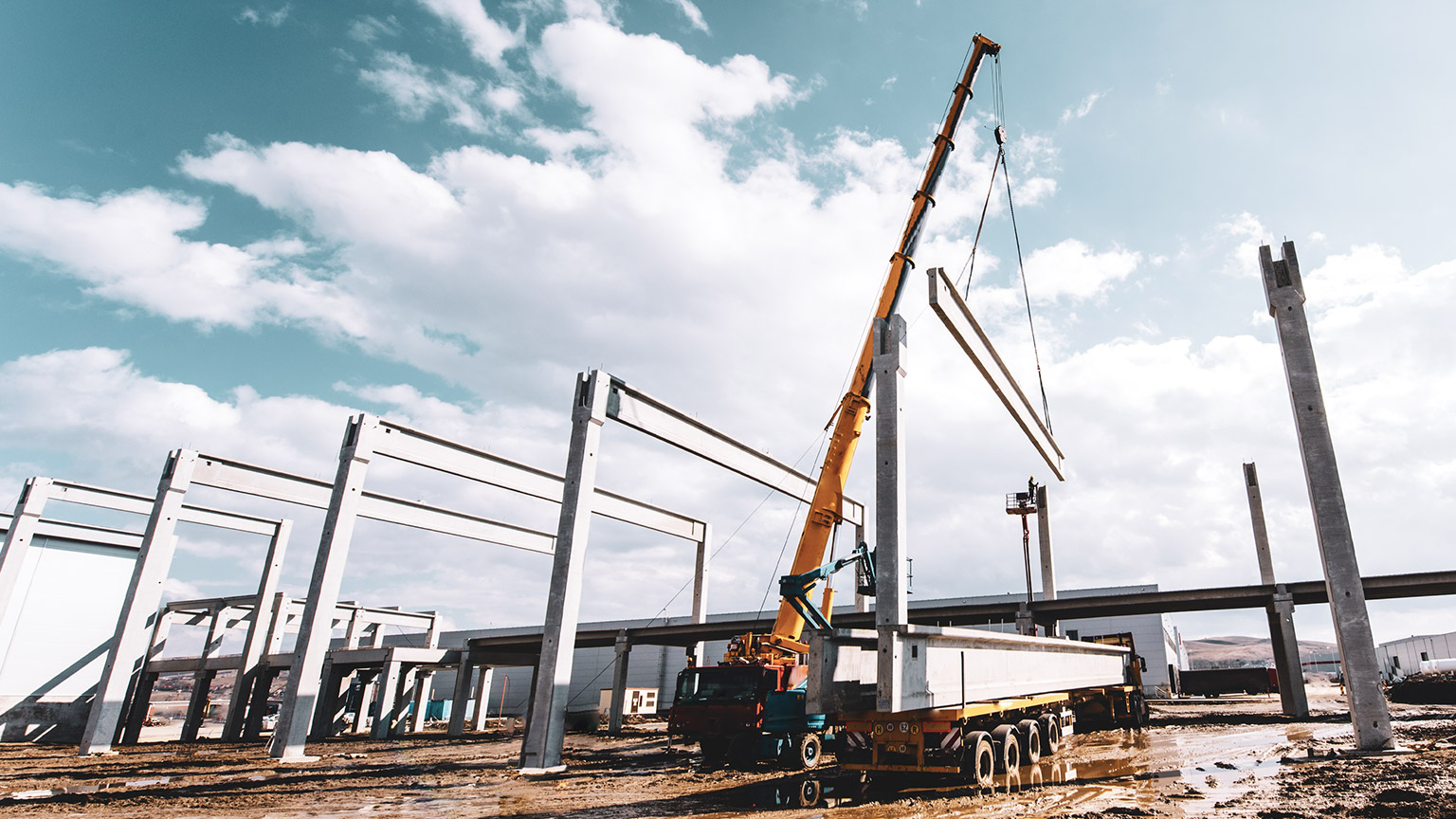 A crane on a building site lifting a large beam into place