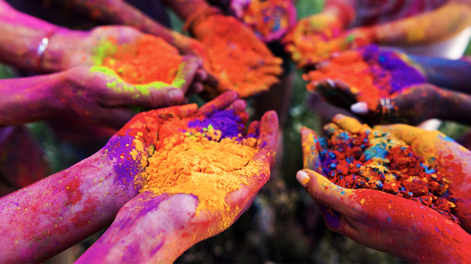 A close up of people's outstretched arms, holding different coloured pigments