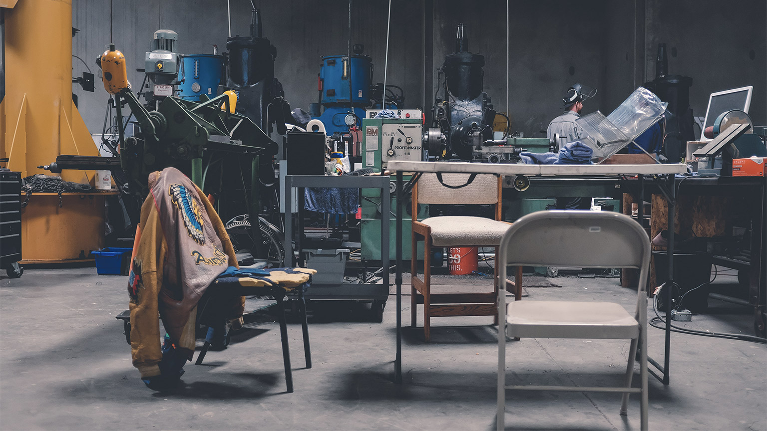 A person standing in their messy, interesting workspace