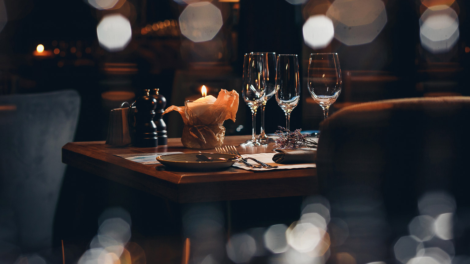 A candle lit dining table as seen through a glass window 