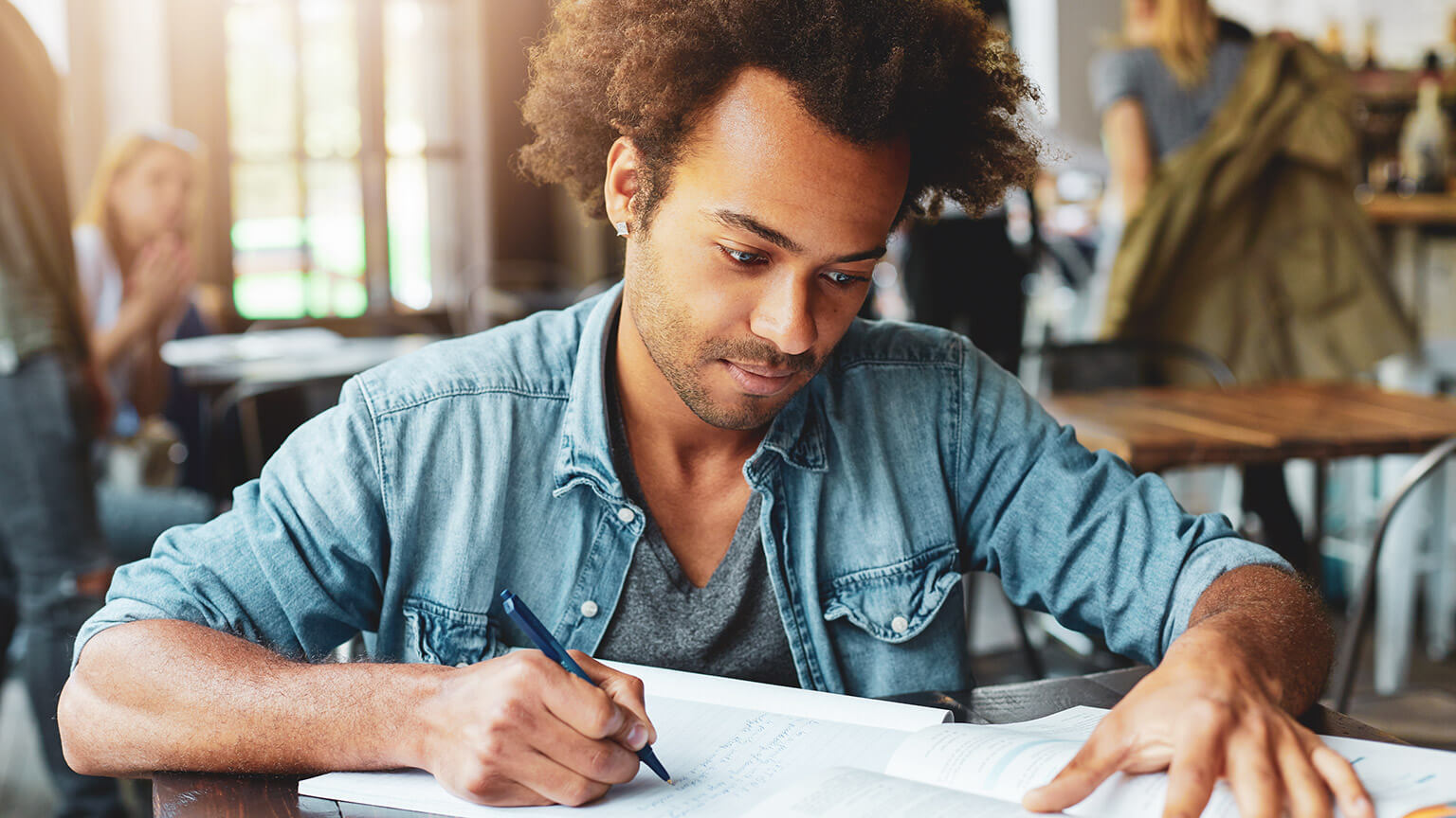 A youth worker reading reference material and writing notes