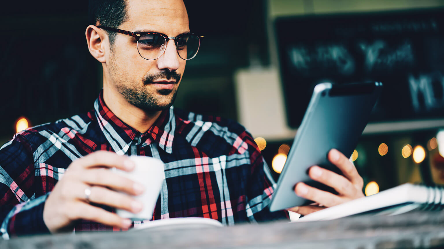 A designer checking out the UI/UX of an app on a tablet device... with a coffee in hand