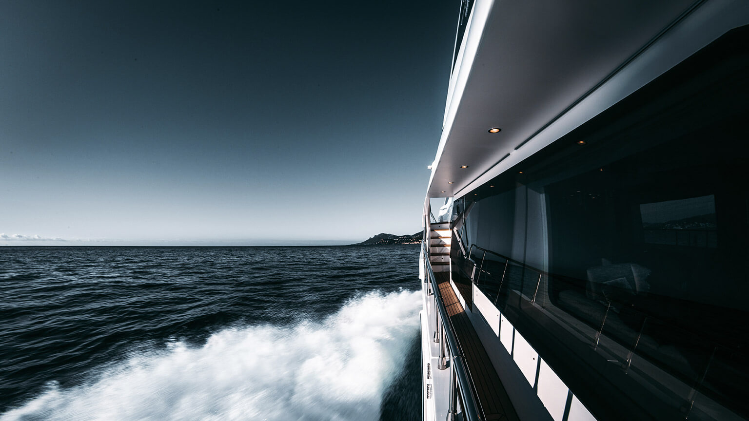 A luxury boat powering through the ocean on a clear day