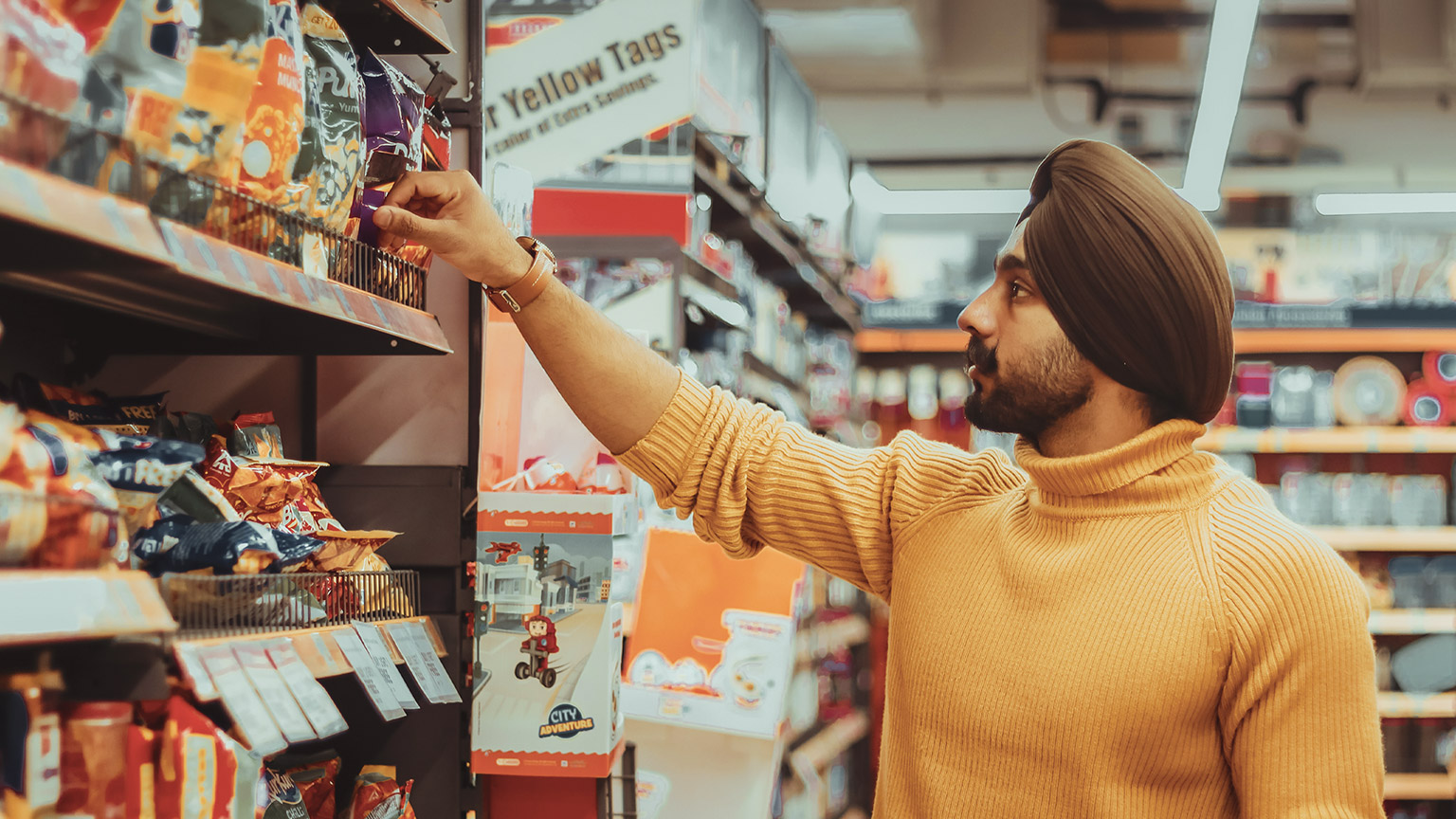 A young male makes a product selection in a supermarket