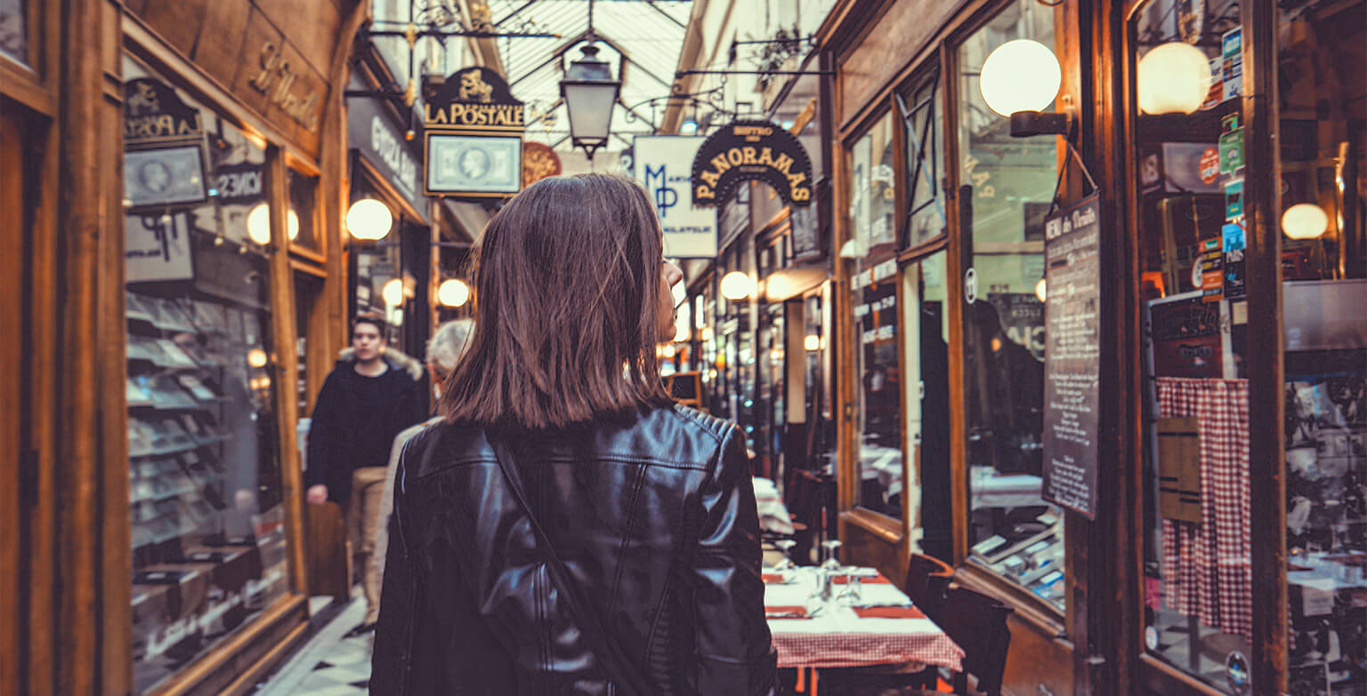 A person venturing down and old arcade, window shopping as they walk