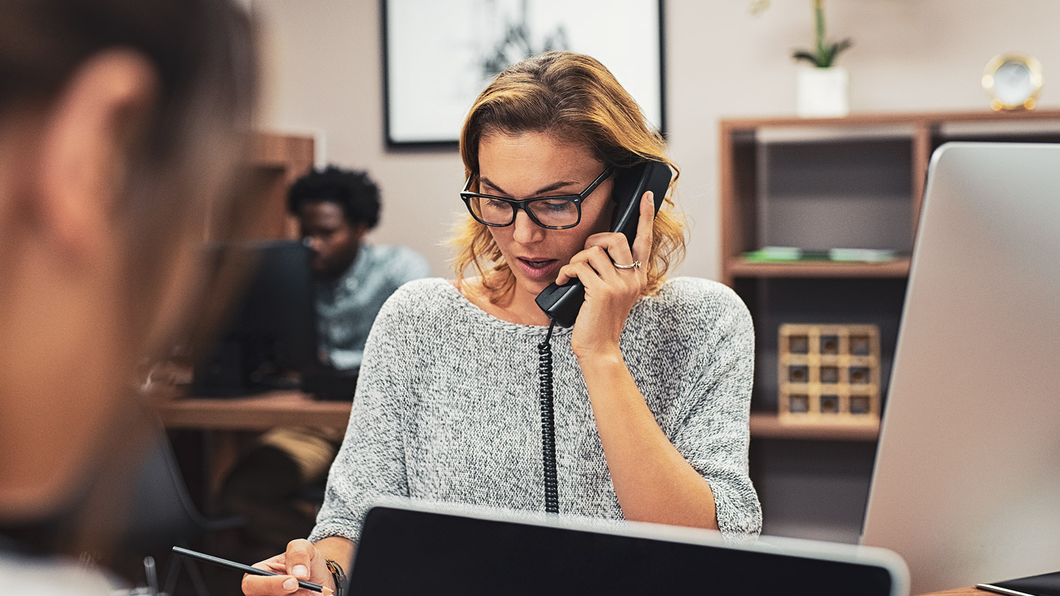 A receptionist talking on the phone and writing down relevant information