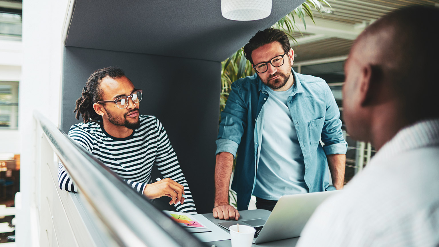 Three coworkers in a meeting area discussing a work project