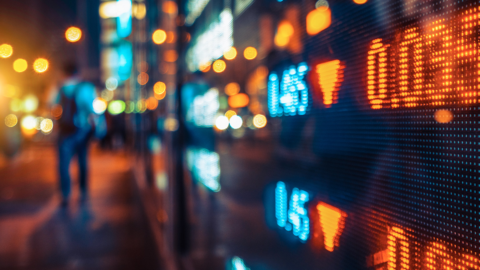 A stock ticker price board in a window of a city street