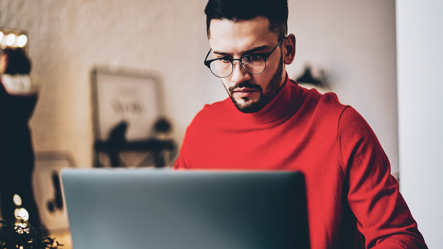 A young designer seated at a desk, working on their laptop