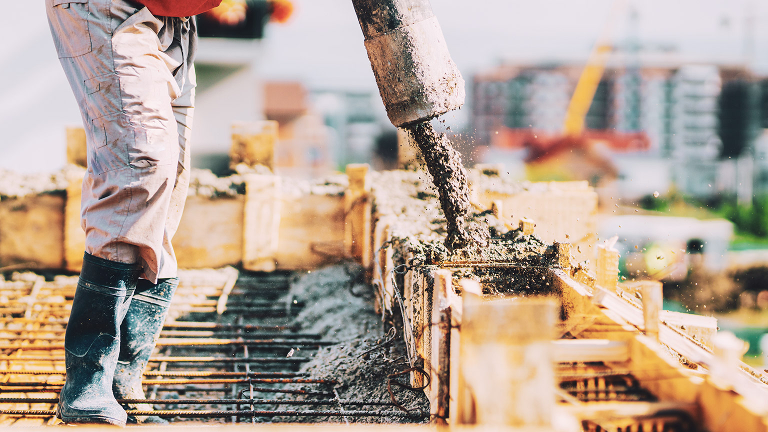 A worker pouring concrete into formwork on a construction site