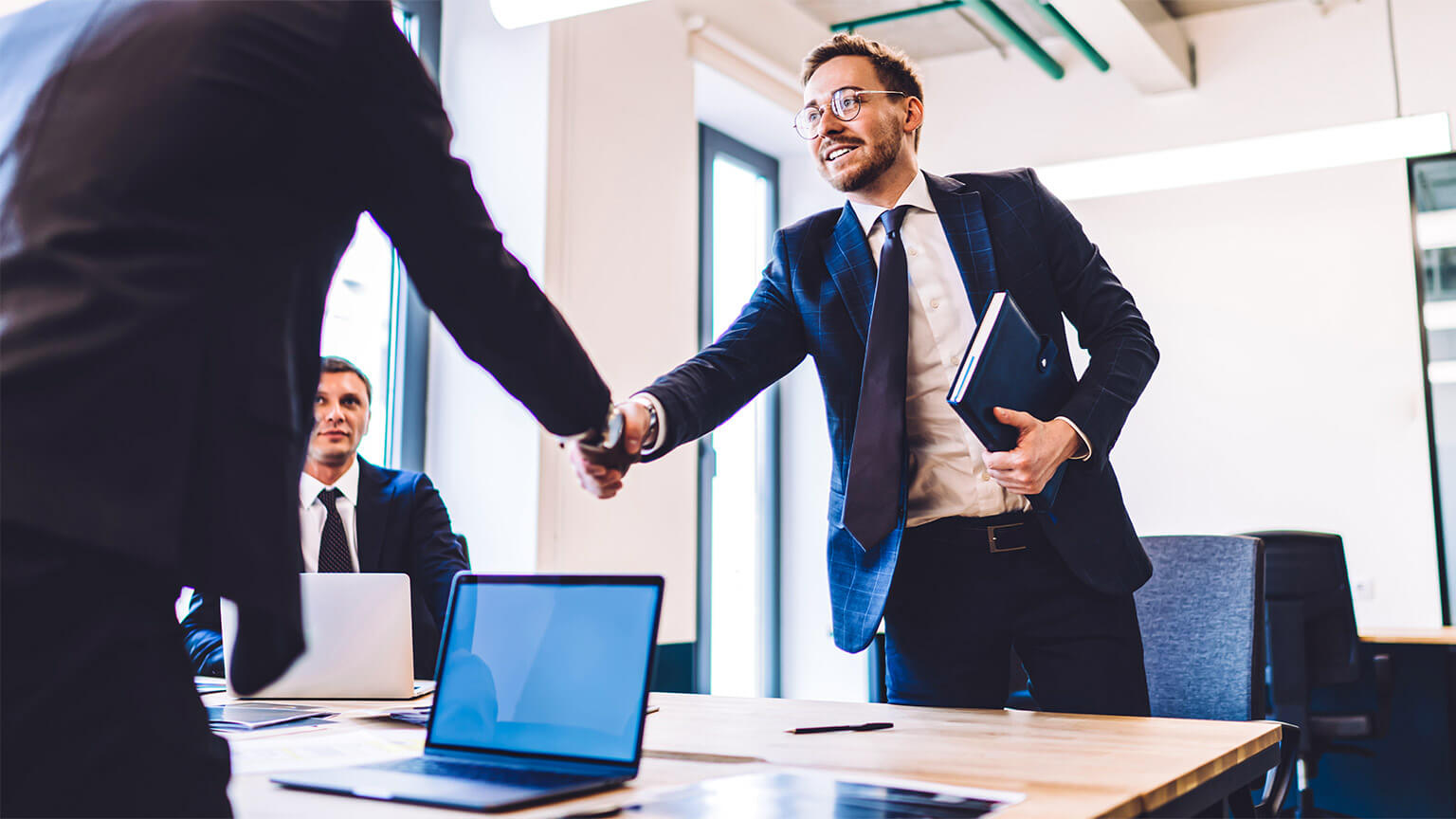 An executive shaking hands with a project lead, acknowledging their recent, successful delivery