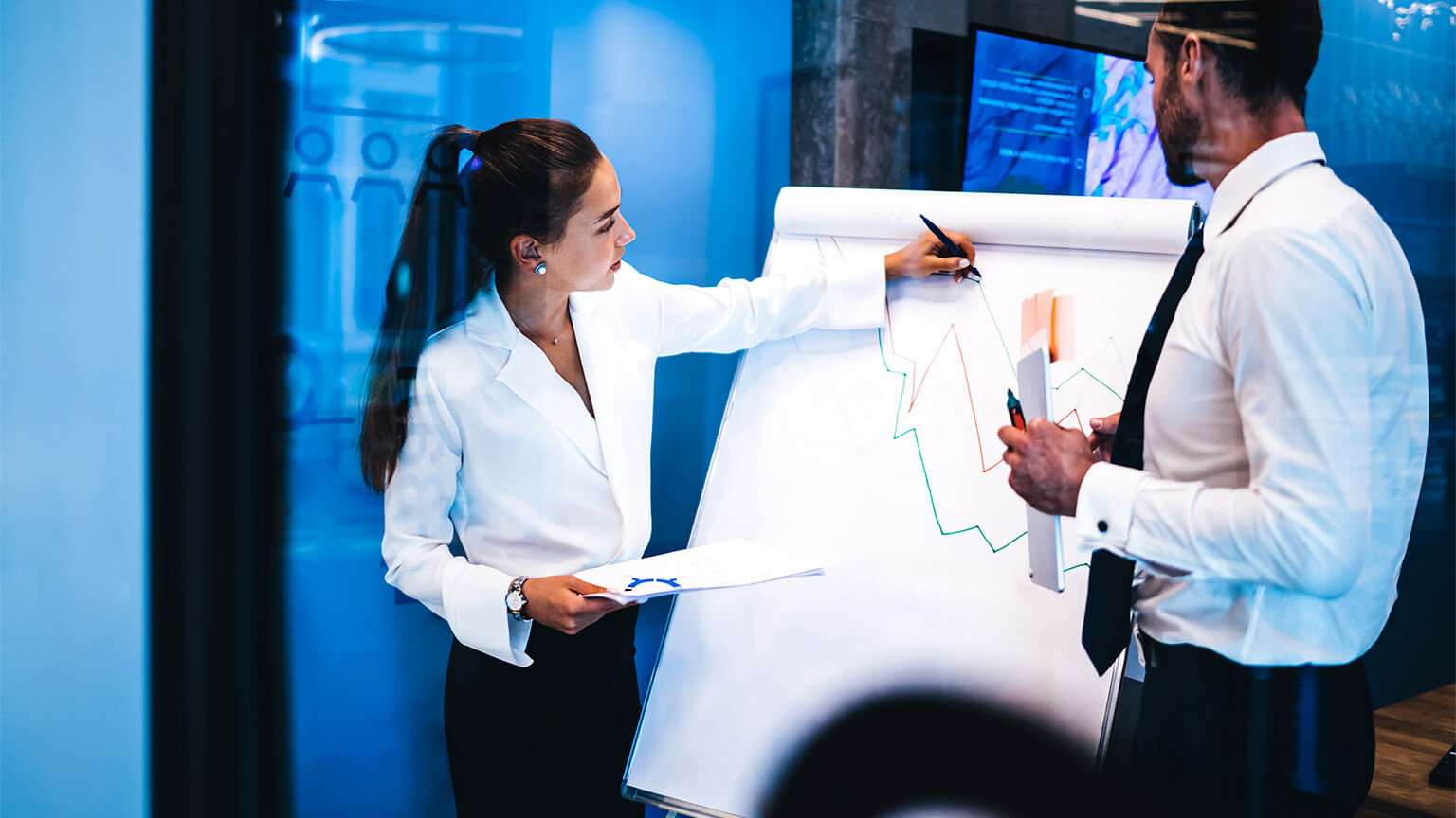 Two colleagues hand drawing a large line chart of data pertaining to the nation's economy