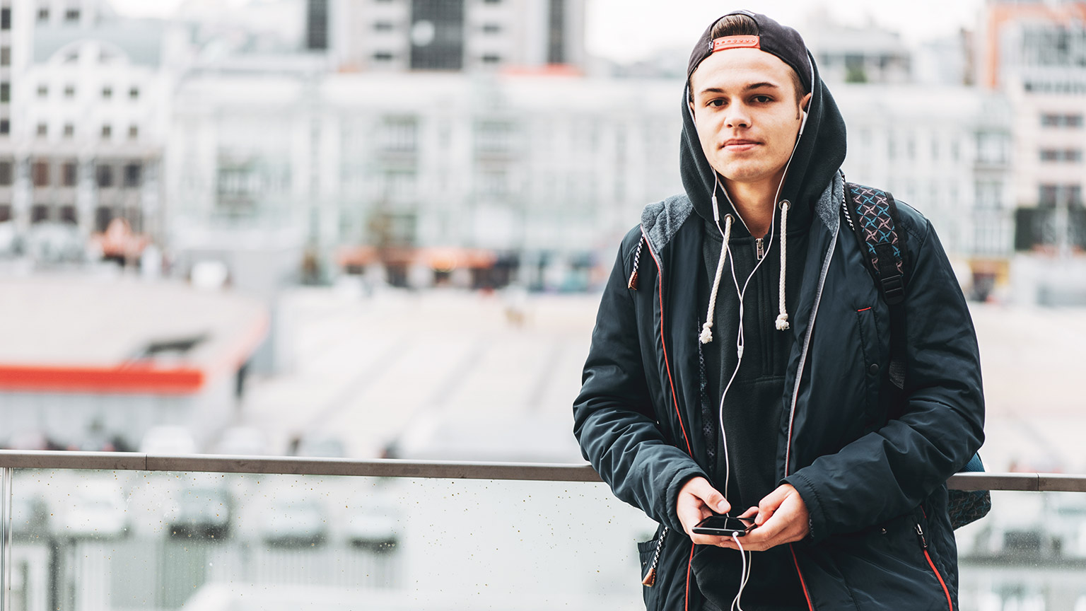 A teenager wearing headphones looking toward the camera with a neutral expression on his face