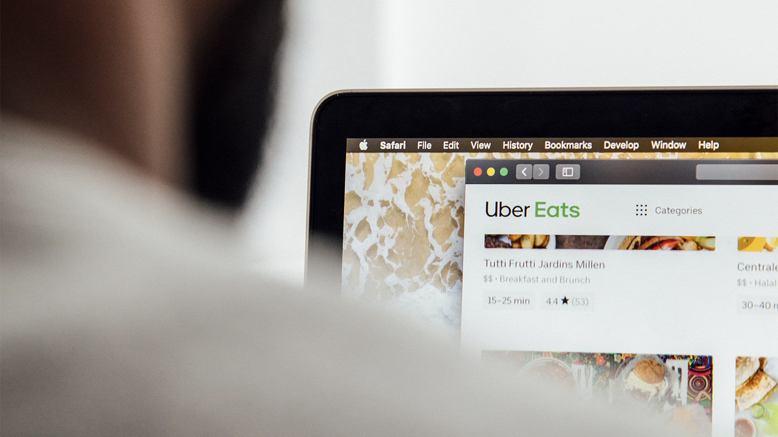 An Uber Eats user sitting on the couch, ordering a meal using their laptop