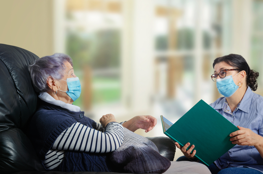 An everyday female caregiver reads books for an elderly woman