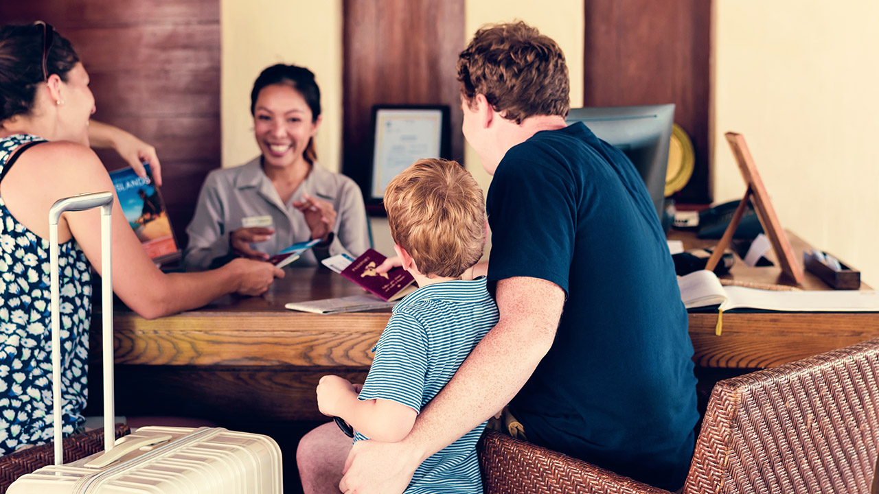 Family at counter of a hotel talking to staff member